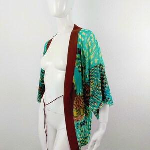 May include: A turquoise and brown patterned kimono with a brown sash. The kimono has a geometric pattern with a bird design.