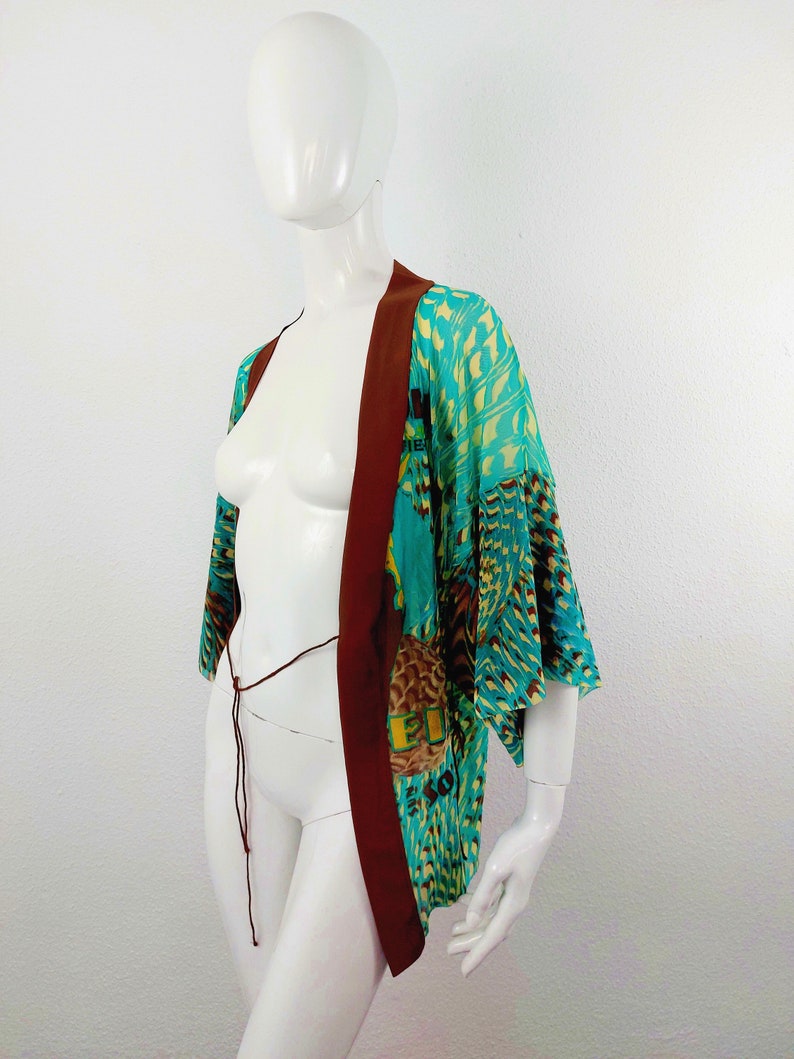 May include: A turquoise and brown patterned kimono with a brown sash. The kimono has a geometric pattern with a bird design.