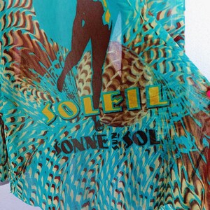 May include: A turquoise blue sheer fabric with a brown silhouette of a person and the words "SOLEIL" and "CONNESOL" printed in yellow.