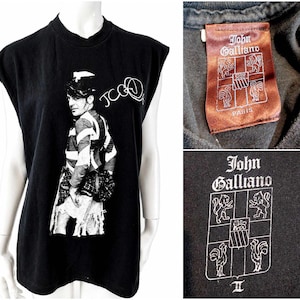 Può includere: T-shirt nero senza maniche con grafica bianca di una persona con giacca a righe e cappello. La maglietta ha il testo "JCOQ" e un'etichetta "John Galliano".