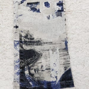 May include: A pair of blue and white patterned pants with a black and white abstract design. The pants have a frayed hem and a blue and white stripe along the bottom.