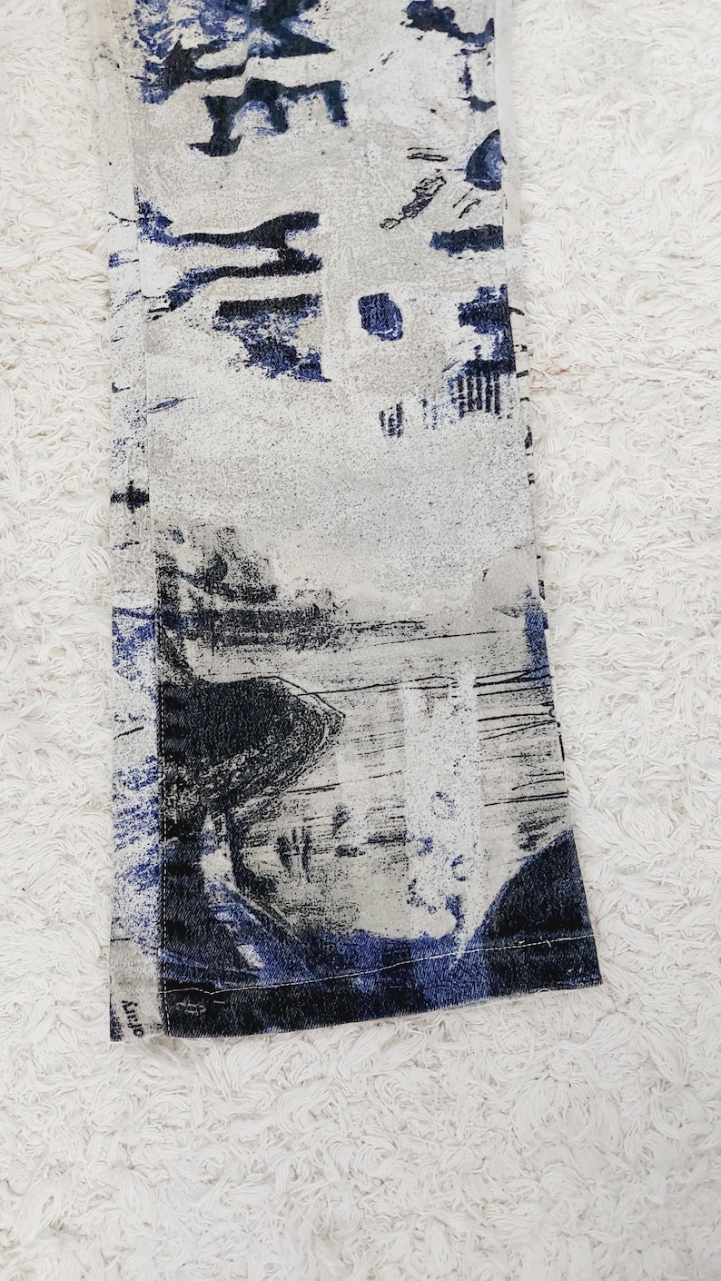 May include: A pair of blue and white patterned pants with a black and white abstract design. The pants have a frayed hem and a blue and white stripe along the bottom.