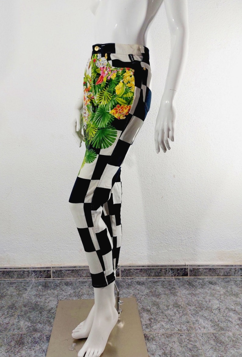May include: Black and white checkered pants with a tropical floral print on the front. The pants are made of denim and have a high waist.