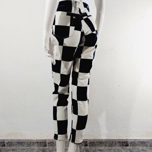 May include: Black and white checkered skinny jeans. The jeans have a high waist and a slim fit.
