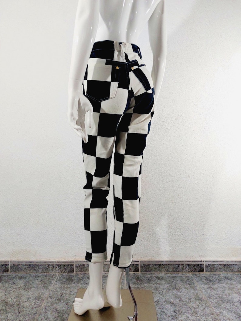 May include: Black and white checkered skinny jeans. The jeans have a high waist and a slim fit.
