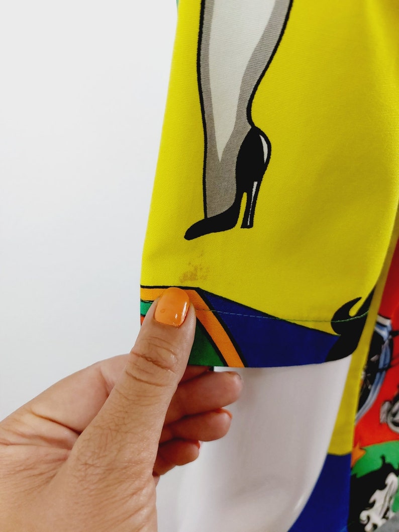 May include: A yellow, blue, green, orange and white patterned fabric with a cartoon image of a woman's leg in a black high-heeled shoe.