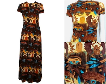 May include: A long, brown maxi dress with a colorful print of eyes, scarabs, and hieroglyphs. The dress has short sleeves and a round neckline.