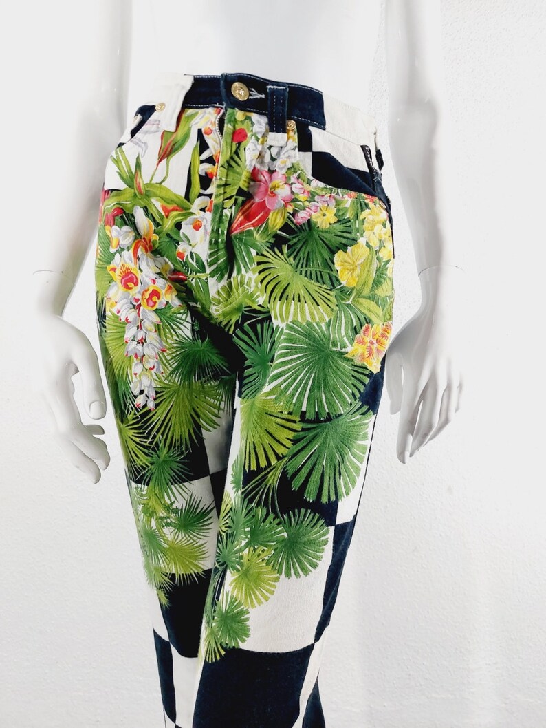 May include: Black and white checkered pants with a tropical floral print. The print features green leaves, yellow and red flowers.