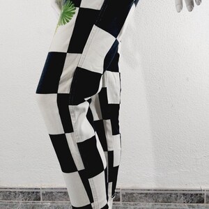 May include: Black and white checkered pants with a green and white tropical leaf print on the side.