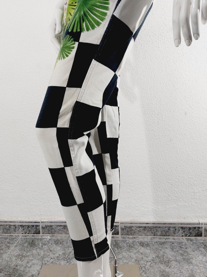 May include: Black and white checkered pants with a green and white tropical leaf print on the side.