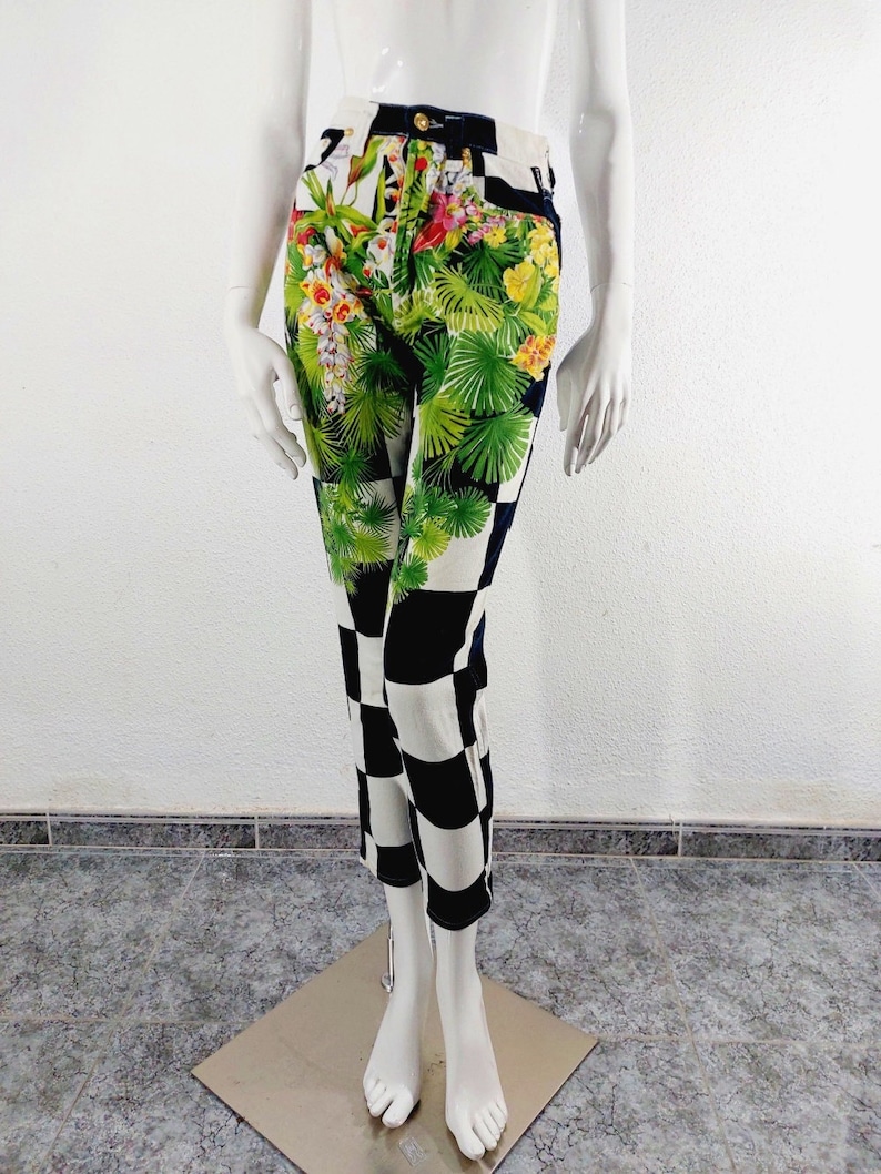 May include: High-waisted jeans with a black and white checkered pattern on the bottom half and a floral print on the top half. The floral print features tropical leaves, flowers, and birds.