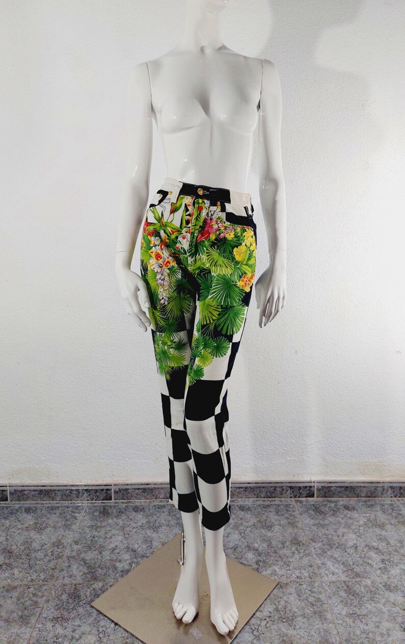 May include: Black and white checkered pants with a floral print on the top half. The floral print features green leaves, pink, yellow, and white flowers.