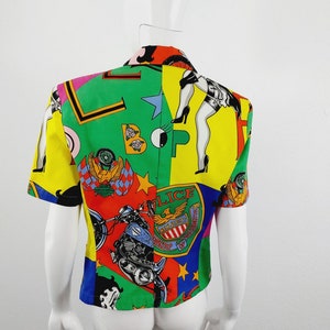 May include: A short-sleeved, multi-coloured button-up shirt with a bold, graphic print featuring a motorcycle, stars, and the words "Police" and "New Jersey".