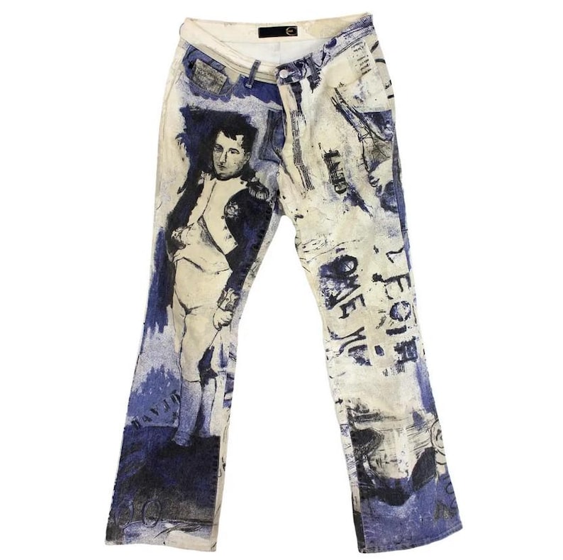 May include: Blue and white printed jeans with a portrait of a man in a military uniform. The jeans have a faded look and are distressed. The text "LEGION ONE" is printed on the right leg.