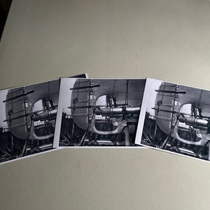 Pu&ograve; includere: Tre fotografie in bianco e nero di una grande struttura metallica in fase di assemblaggio. La struttura &egrave; composta da travi e lamiere metalliche e sembra far parte di una macchina o di un'attrezzatura pi&ugrave; grande. Le fotografie sono scattate da diverse angolazioni, mostrando la struttura da diverse prospettive.