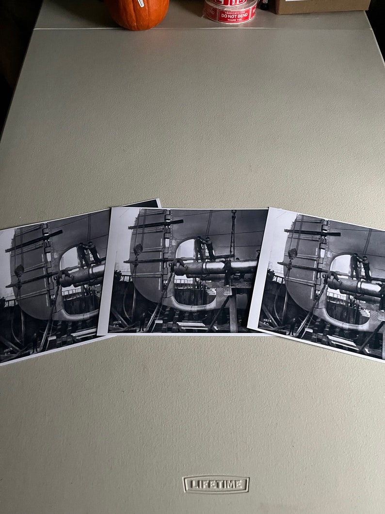 Pu&ograve; includere: Tre fotografie in bianco e nero di una grande struttura metallica in fase di assemblaggio. La struttura &egrave; composta da travi e lamiere metalliche e sembra far parte di una macchina o di un'attrezzatura pi&ugrave; grande. Le fotografie sono scattate da diverse angolazioni, mostrando la struttura da diverse prospettive.