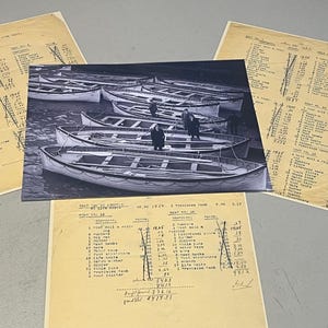 May include: A monochrome photograph showing multiple rowboats on water, with individuals standing on one. The image is accompanied by aged, handwritten documents featuring lists and figures.