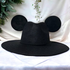 May include: A black felt fedora hat with large, round, black ears attached to the sides, resembling Mickey Mouse ears.