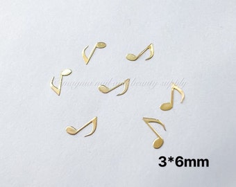 Könnte beinhalten: Goldene Musiknoten-Nagelkunst-Anhänger. Das Bild zeigt sieben Anhänger, jeder misst 3 mm x 6 mm.