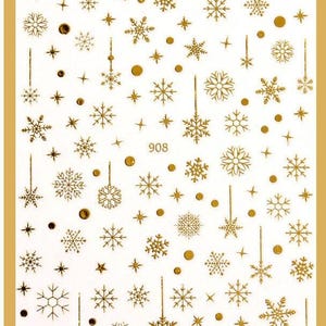 May include: Gold snowflake and star nail stickers. The sheet features a variety of snowflake and star designs in gold foil.