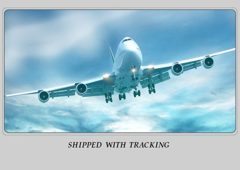 May include: A large white passenger airplane in flight against a blue sky with clouds. The plane has four engines and its landing gear is down. The text "SHIPPED WITH TRACKING" is at the bottom of the image.