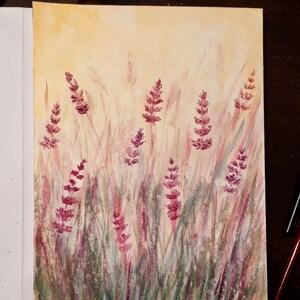 K&ouml;nnte beinhalten: Aquarellmalerei von Lavendelbl&uuml;ten in einem Feld. Das Kunstwerk zeigt lila Lavendelbl&uuml;ten und gr&uuml;nes und lila Gras vor einem gelben und beigen Hintergrund. Das Gem&auml;lde befindet sich auf wei&szlig;em Papier.