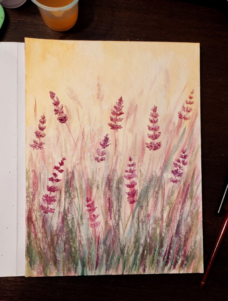 K&ouml;nnte beinhalten: Aquarellmalerei von Lavendelbl&uuml;ten in einem Feld. Das Kunstwerk zeigt lila Lavendelbl&uuml;ten und gr&uuml;nes und lila Gras vor einem gelben und beigen Hintergrund. Das Gem&auml;lde befindet sich auf wei&szlig;em Papier.