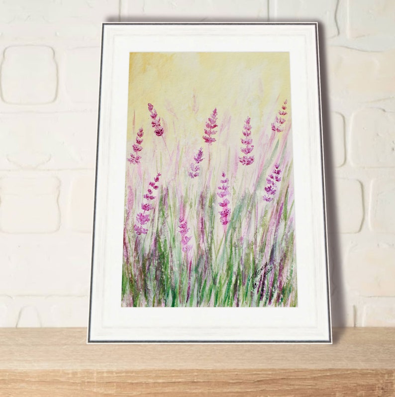 K&ouml;nnte beinhalten: Gerahmtes Aquarellgem&auml;lde von Lavendelbl&uuml;ten in einem Feld. Das Kunstwerk zeigt lila Lavendelbl&uuml;ten inmitten von gr&uuml;nem Gras, vor einem weichen gelben Hintergrund. Das Gem&auml;lde befindet sich in einem wei&szlig;en Rahmen.