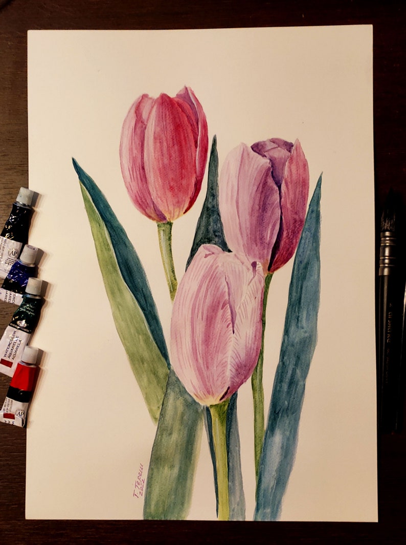 May include: Watercolor painting of three tulips in shades of pink and purple, with green leaves. The artwork is on white paper, with tubes of watercolor paint and paintbrushes visible. The painting is signed and dated.