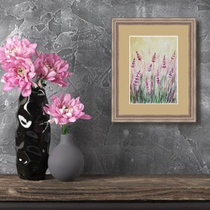 K&ouml;nnte beinhalten: Gerahmtes Gem&auml;lde mit Lavendelbl&uuml;ten auf einem Holzregal. Zwei Vasen, eine schwarze und eine graue, enthalten rosa Chrysanthemen. Der Hintergrund ist eine strukturierte graue Wand. Das Kunstwerk erinnert an die Natur.