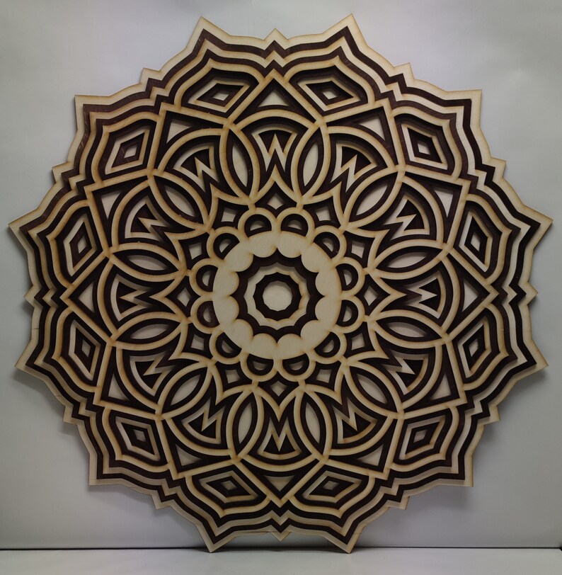 May include: A layered wooden mandala wall art piece. The design features concentric circles with intricate geometric patterns. The wood has a natural, light color with darker brown accents, creating a striking contrast. The artwork is circular and appears to be approximately 24 inches in diameter.