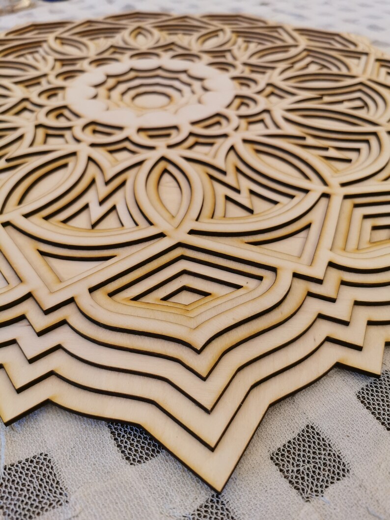 May include: A layered wooden mandala with a complex geometric design. The natural wood tones create a warm aesthetic. The circular artwork features intricate patterns and shapes, perfect for wall decor.