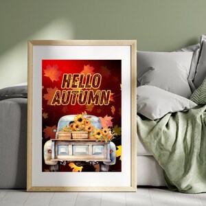 Könnte beinhalten: Gerahmter Druck mit einem blauen Oldtimer-Pick-up, beladen mit Sonnenblumen und Holzkisten. Der Hintergrund ist ein tiefes Rot mit Herbstblättern und dem Schriftzug "HELLO AUTUMN" in Gold.