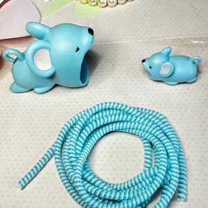May include: A light blue mouse-shaped object with a large opening, a smaller mouse figurine, and a coiled blue and white striped cord. A pearl necklace and floral cutouts are in the background.