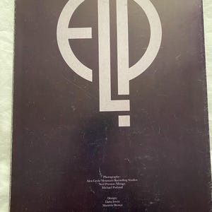 May include: A dark brown album cover featuring a large, stylized white "ELP" logo. The cover includes text with photography and design credits, along with the address of Brokum International Inc. in New York.
