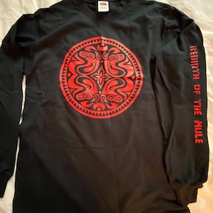 May include: Black long-sleeve shirt with a large red circular design on the front. The design features an intricate pattern. The right sleeve has the text "REBIRTH OF THE MULE" printed vertically in red.