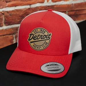 May include: Red and white trucker hat with a brown leather patch that says "Est. 1926 Detroit Hockey Club".