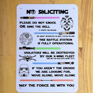 May include: White metal sign featuring Star Wars-themed text and graphics. The sign reads "No Soliciting" and includes phrases like "This Battle Station Is Fully Operational" and "May The Force Be With You."
