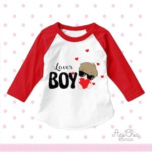 May include: White and red baseball tee shirt with the text "Lover Boy" in black. A cartoon boy wearing sunglasses is holding a red heart.