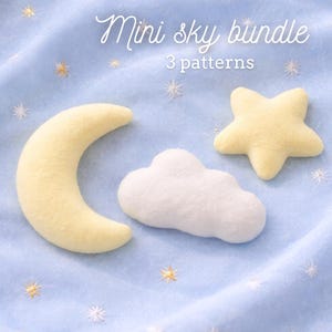 Puede incluir: Un juego de manualidades de fieltro con una luna creciente amarilla, una nube blanca y una estrella amarilla. Las palabras "Mini sky bundle" y "3 patterns" están escritas en cursiva. Los artículos están sobre una tela azul claro con estrellas bordadas.