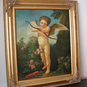 May include: A framed oil painting of a cherub holding a bow and arrow in a lush garden setting. The cherub is depicted with wings and a rosy complexion, surrounded by vibrant green foliage and pink roses.
