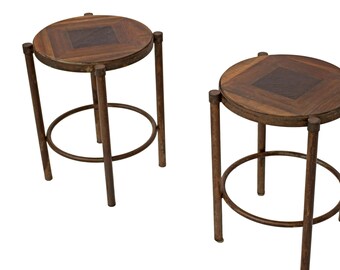 May include: Two round wooden side tables with a metal frame. The tabletops have a geometric pattern of inlaid wood.