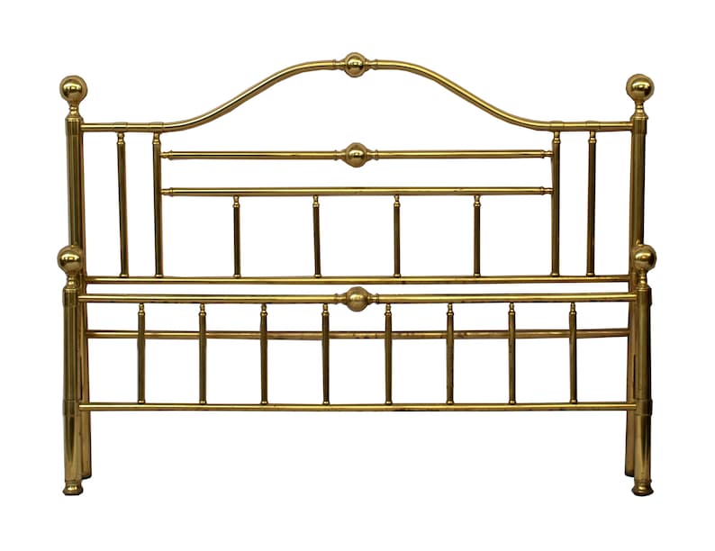May include: A gold-colored metal bed frame with a headboard. The headboard has a curved top with decorative ball finials and horizontal bars. The frame has vertical supports and additional decorative elements.