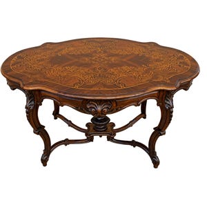 Könnte beinhalten: Ein ovaler Couchtisch aus dunklem Holz mit aufwendigen Intarsien auf der Tischplatte und geschnitzten Beinen.