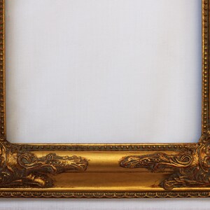 K&ouml;nnte beinhalten: Ein goldener Bilderrahmen mit verzierten Details an den R&auml;ndern. Der Rahmen ist aus Holz und hat eine Antik-Optik.
