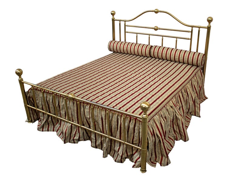 May include: A brass bed frame with a striped comforter and a matching bed skirt. The comforter and skirt feature a pattern of red and beige vertical stripes. A cylindrical bolster pillow rests at the head of the bed.