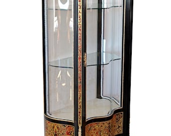 May include: A black display cabinet with glass doors and shelves. The cabinet has gold accents and ornate red and gold floral designs on the lower portion. The cabinet has curved sides and stands on four curved legs.