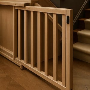 K&ouml;nnte beinhalten: Helle Holz-Kinderschutzt&uuml;r mit vertikalen Sprossen. Die T&uuml;r ist an einer Holzkonstruktion befestigt und befindet sich in der N&auml;he einer Treppe mit beigefarbenen Teppichstufen. Schlichtes, modernes Design.