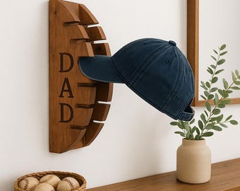 May include: A wooden baseball cap holder with the word "DAD" carved into it. A navy blue baseball cap is displayed on the holder. A woven basket with baseballs and a small vase with greenery are also visible.