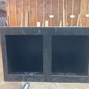 May include: A black wooden cabinet with two open compartments. The cabinet has a rough, textured surface.